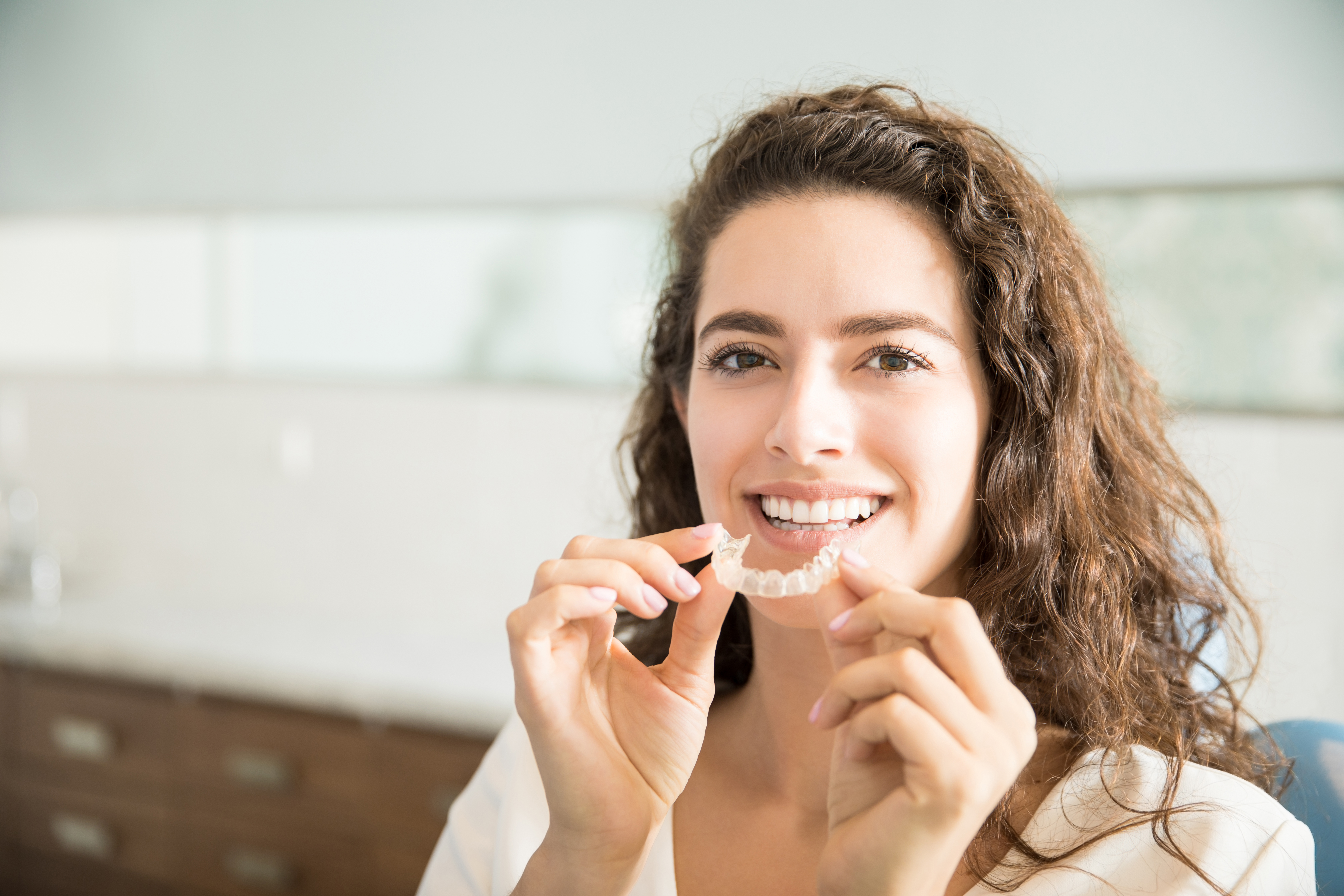 A woman holding clear aligners
